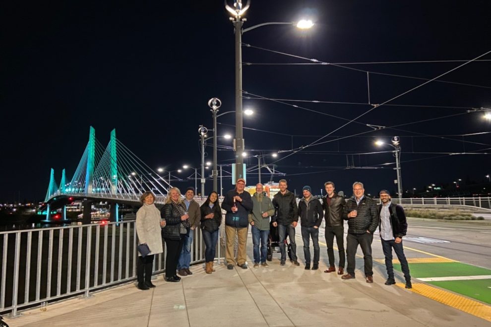 A team of lighting agents stand outside a lit bridge at night.