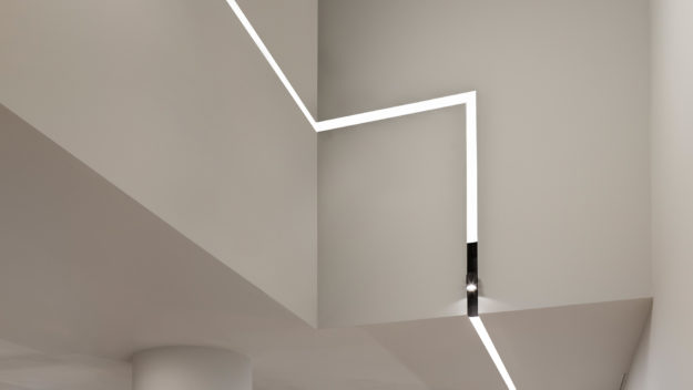 Architectural linear lighting in a zig-zag configuration recessed into a ceiling and wall